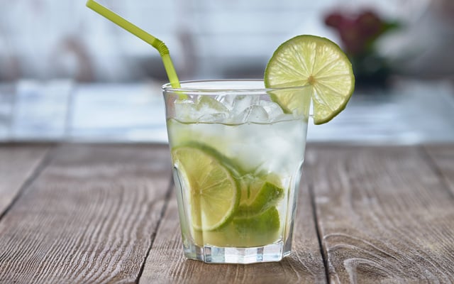 Caipirinha com gelo e rodela de limão no copo com canudo