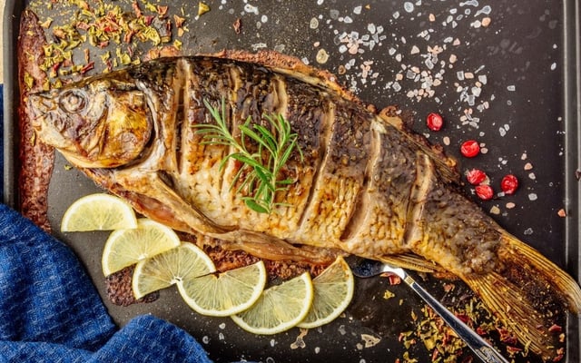 Peixe assado com recheio em travessa com rodelas de limão