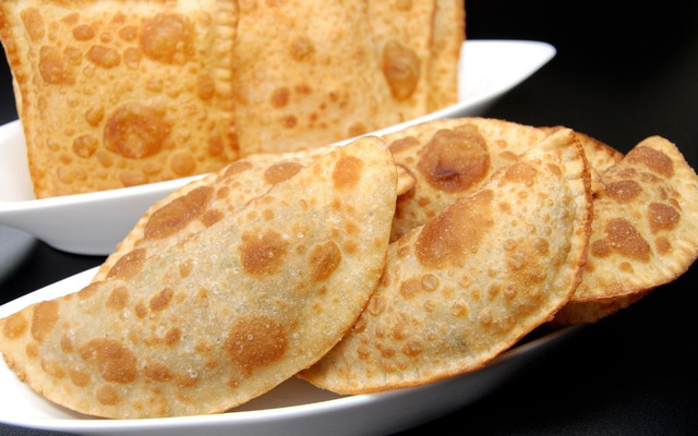 Pastel em forma de meia lua e em quadrado em duas tigelas