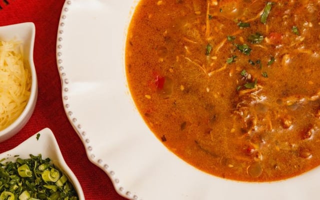 Caldo de kenga finalizado com cheiro-verde servido em prato