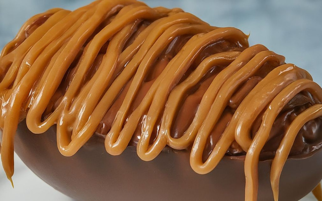 Ovo de chocolate recheado com paletas e coberto com calda de caramelo salgado