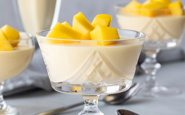 Mousse de manga cremosa servida em taça com pedaços da fruta