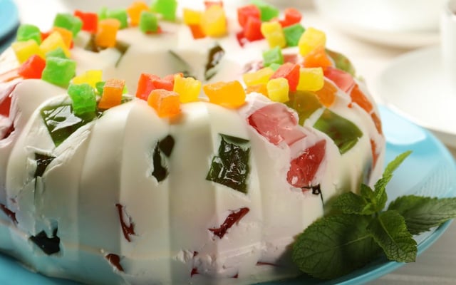 Gelatina colorida com creme de leite condensado e frutas em cima