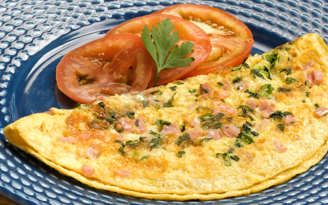 Omelete simples dobrada decorada com salsinha e tomate