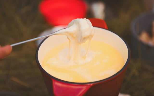 Fondue de queijo sem lactose cremoso escorrendo de um pão