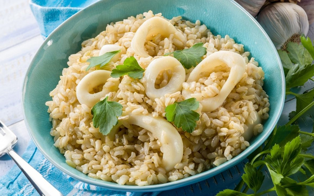 Risoto de lula em anéis em prato finalizado com coentro