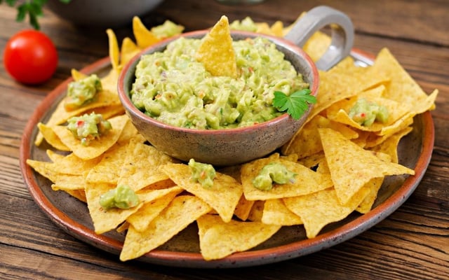 Tigela de guacamole com nachos caseiros ao redor