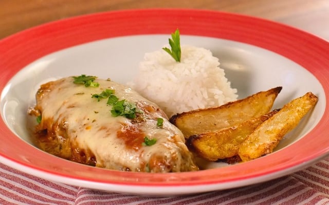 Bife à parmegiana no prato completo com batata e arroz