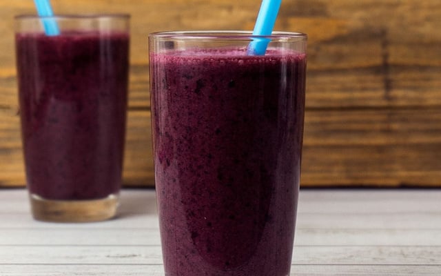 Suco de jabuticaba em copo de vidro servido com canudo