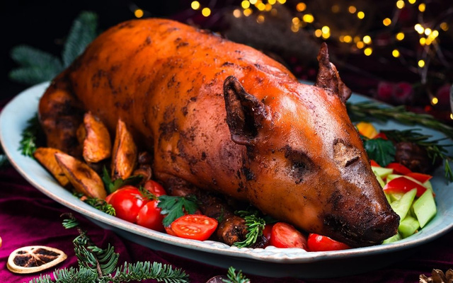 Leitoa à pururuca servida em prato com batatas e tomates