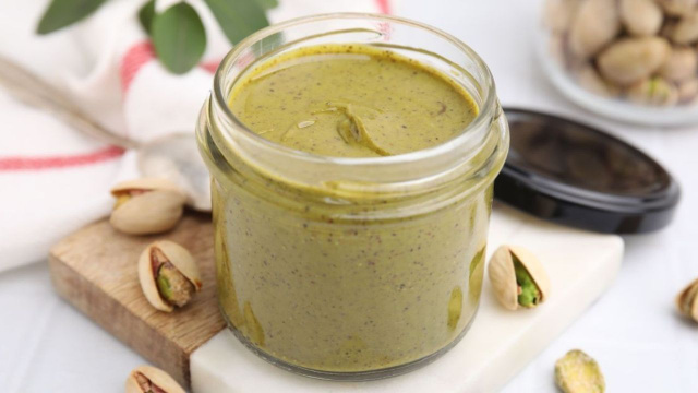 Pasta de pistache caseira e cremosa em um potinho com sementes de pistache cru (Créditos: Shutterstock)