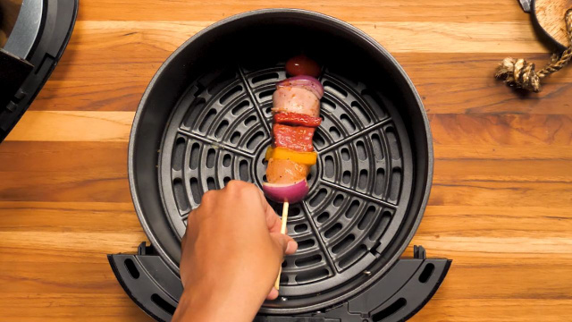 Espetinho de churrasquinho sendo colocado dentro do cesto da air fryer (Créditos: TudoGostoso)