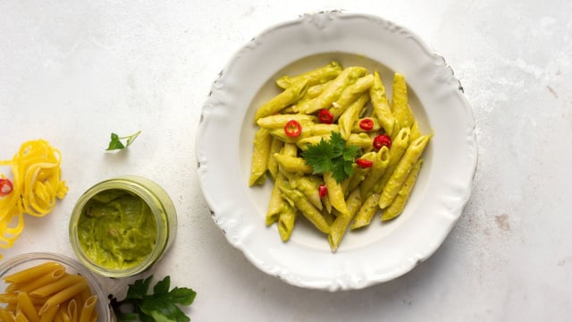 Macarrão com molho pesto de pistache acompanhados por folhas de manjericão e fatias de pimenta vermelha (Créditos: Camponesa)