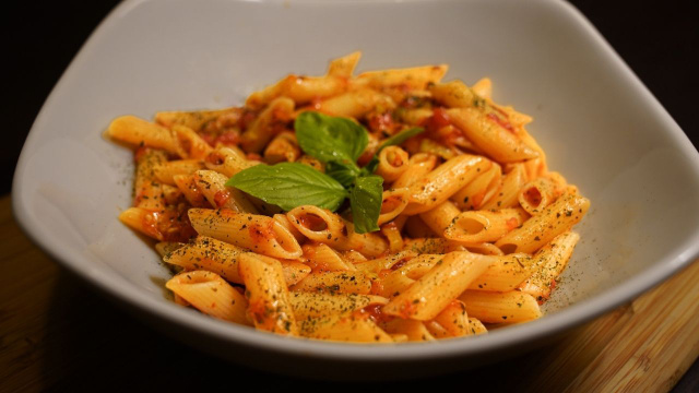 Penne com manjericão e alho-poró com molho de tomate em prato (Créditos: Shutterstock)