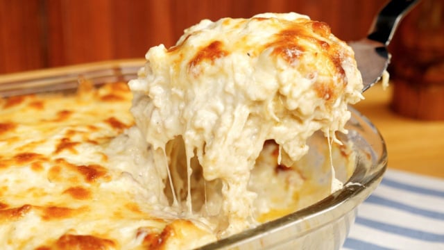 Fatia de lasanha de frango com queijo e molho branco cremoso retirada de travessa (Créditos: TudoGostoso)