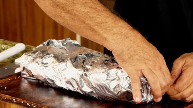 A primeira etapa da receita é assar a costela em um envelope de papel-alumínio com água (Créditos: Reprodução/TV Churrasco/YouTube)