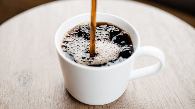 Café preto puro sendo despejado na xícara (Créditos: Canva)