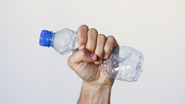 Garrafa plástica de água sendo amassada (Créditos: Canva)