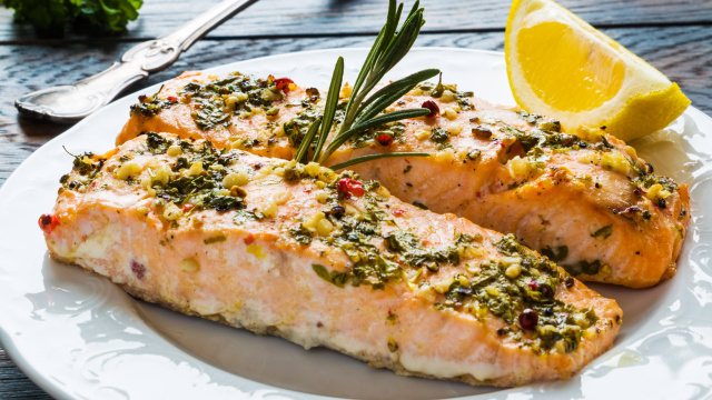 Dois pedaços de filé de salmão ao forno suculentos com temperos por cima e meio limão para servir (Créditos: TudoGostoso)