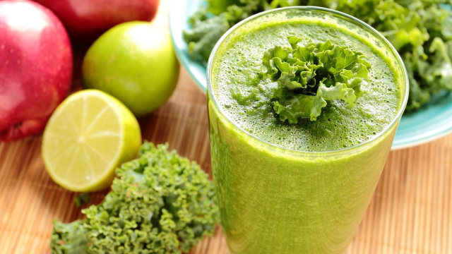 Suco detox de couve, maçã e limão com coloração verde decorado com folhas de couve (Créditos: Shutterstock)