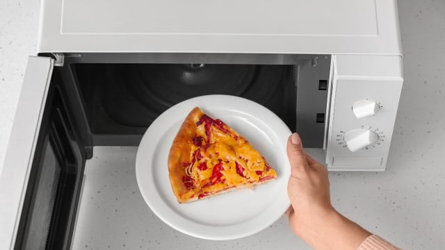O micro-ondas aquece a água presente na massa da pizza, deixando-a borrachuda, e ela logo fica dura (Créditos: Shutterstock)