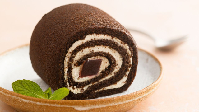  
Rocambole gelado de leite em pó e chocolate com recheio cremoso de coco em prato (Créditos: Shutterstock)