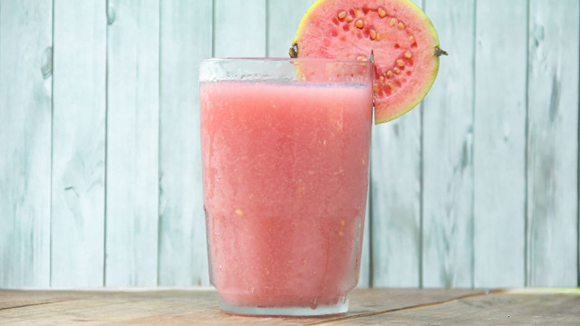 Suco de goiaba rosinha em copo decorado com rodela da fruta (Créditos: Shutterstock)