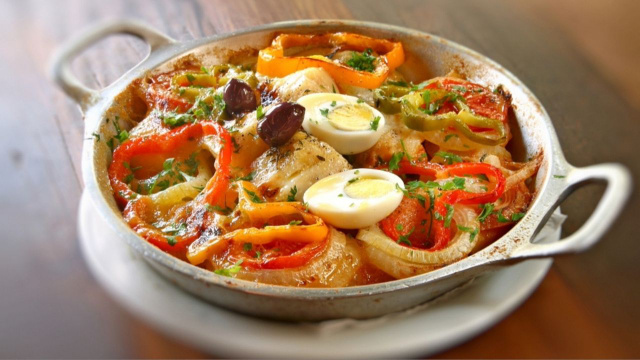 Bacalhoada com ovo cozido, pimentões, cebola, tomates e azeitonas pretas em uma panela grande (Créditos: TudoGostoso)
