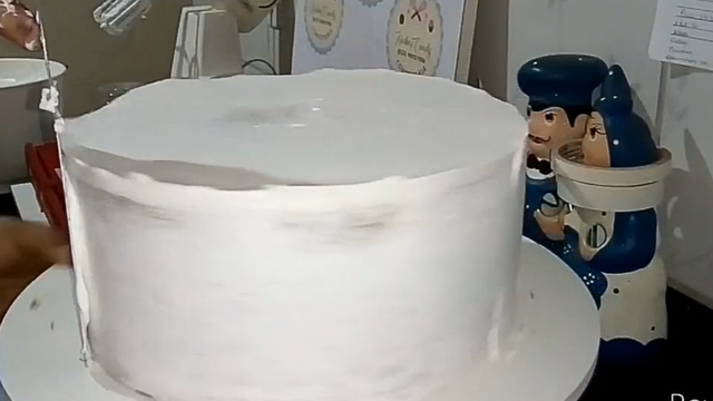 A primeira camada deve ser bem fina e lisinha para servir como base para a decoração (Créditos: Reprodução / YouTube @festejandocomalu7674)