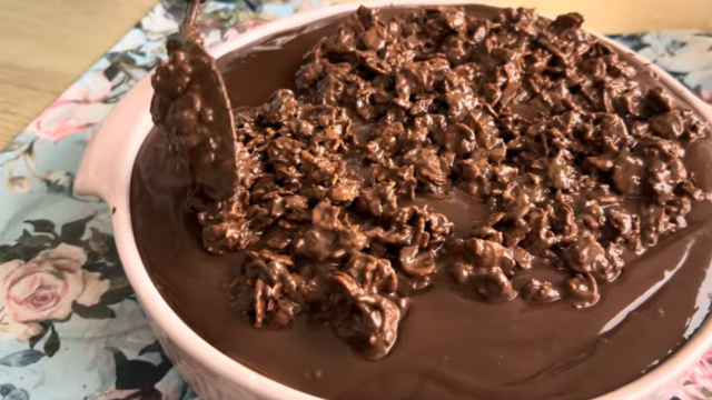 Depois de espalhar a ganache por cima do bolo, finalize com a cobertura crocante (Créditos: Reprodução/ YouTube @AgradávelCozinha)