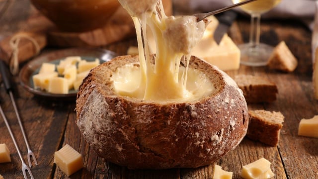 Fondue de queijo no pão italiano grande e redondo com pedacinhos de pães (Créditos: Shutterstock)