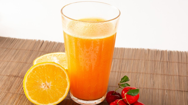 Suco de laranja com acerola com as duas frutas ao lado (Créditos: Shutterstock)