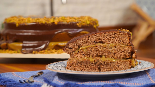 Fatia de bolo de chocolate com pistache como recheio e coberto por ganache (Créditos: TudoGostoso)