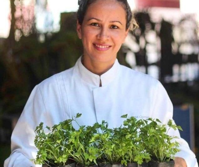 Vestida com um dolmã branco, a chef mineira Luciana Castrioto segura mudas de temperos 