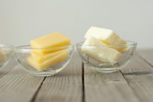 Recipiente com pedaços de manteiga ao lado de um recipiente com pedaços de queijo