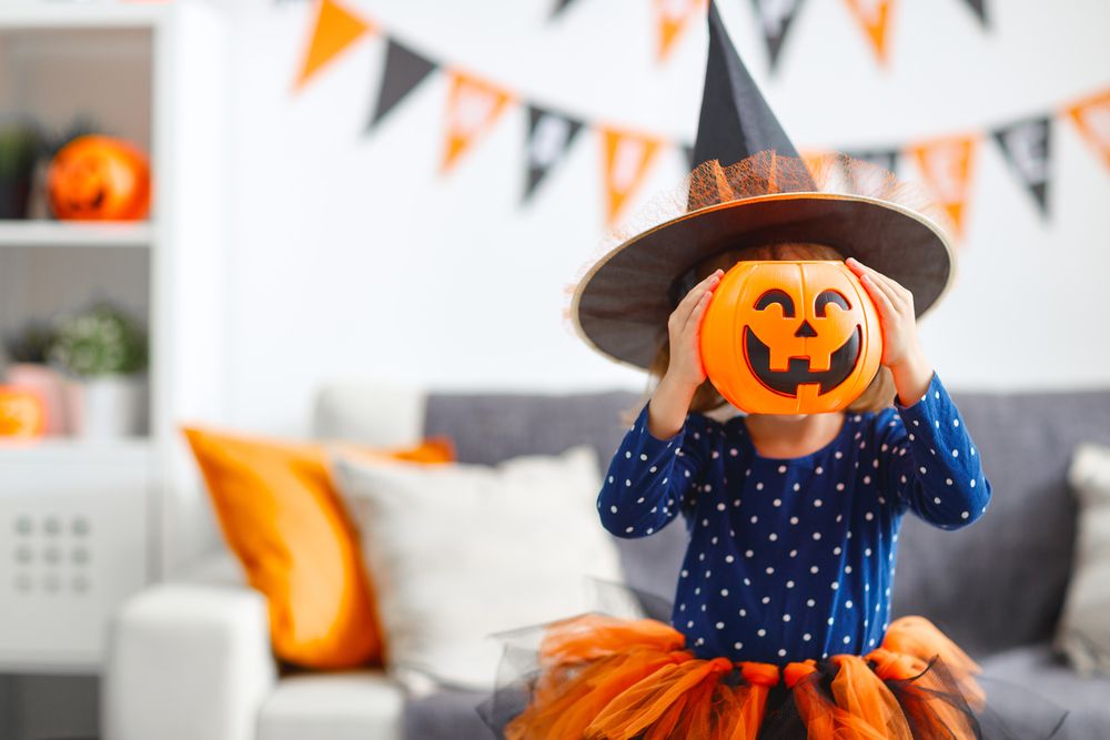Festa de Halloween: menina vestida de bruxa segurando uma abobora de halloween no lugar da cabeça