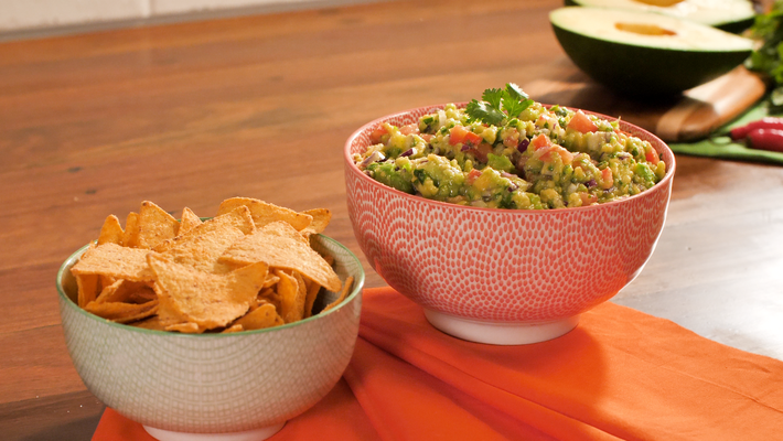 receita de guacamole em um bowl, em cima de uma toalha laranja