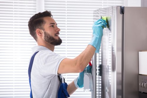 Homem limpando geladeira de inox
