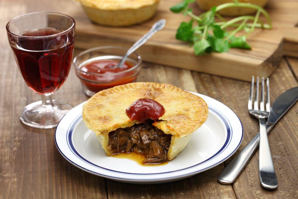comida australiana com torta de carne individual com molho por cima