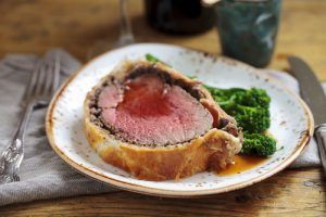 Bife Wellington com molho e acompanhado de brócolis