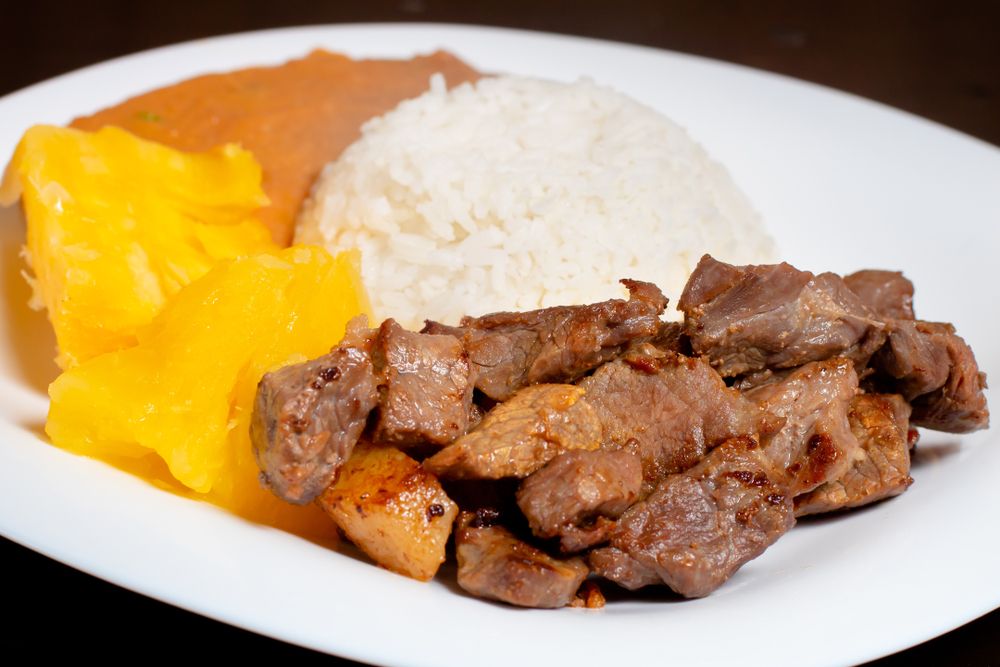 prato branco com carne de sol, macaxeira, arroz e feijão: receitas com macaxeira